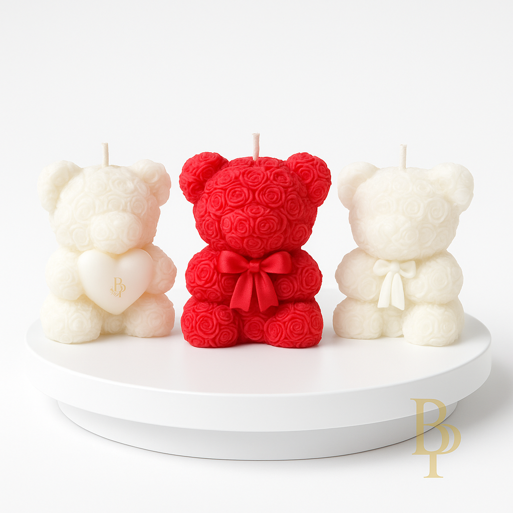 Three bear-shaped candles, one red with a bow, and two white, on a white platform.